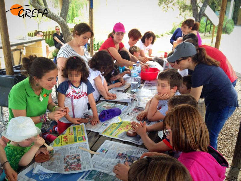Varios niños apuntados al campamento de verano de GREFA de 2017 participan en un taller de elaboración de huellas de fauna con arcilla.