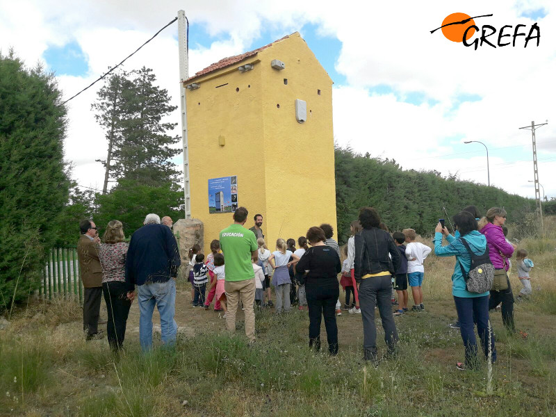 Niños y mayores frente a la caseta de transformador adecuada para fauna en Navas de Riofrío (Segovia).