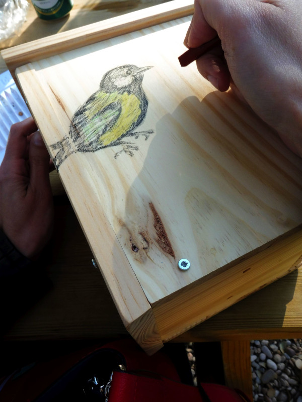Un trabajador de Imasde Agroalimentaria pinta una caja nido para aves durante su visita a GREFA.