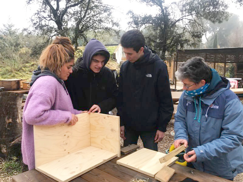 Un grupo de participantes en el Día de la Educación Ambiental construye una caja nido, junto con una educadora de GREFA.