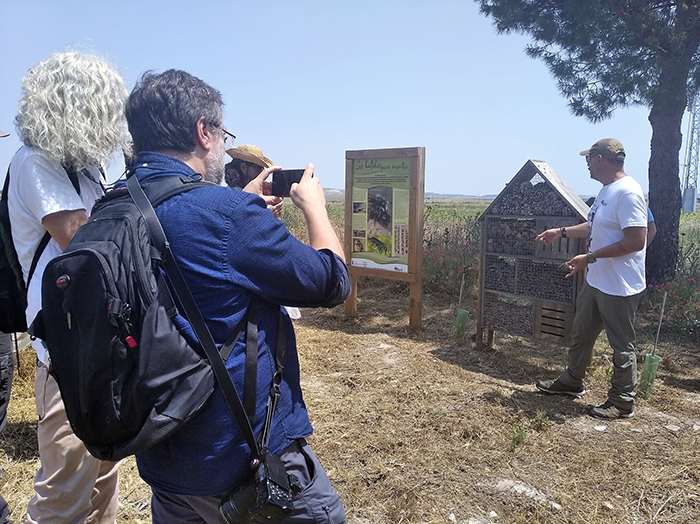 Fernando Blanca, de GREFA, explica a los periodistas la importancia de las abejas silvestres junto a un cartel dedicado a estas especies y un "hotel de insectos" en nuestra parcela experimental "Las Pozas".