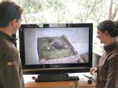 Sandra y Pablo sonrien ante la buena noticia, mientras observan la puesta de las águilas perdiceras en una de las pantallas de educación ambiental